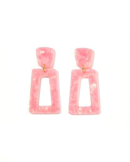 The Kennedy Earrings have a pink marbled resin geometric design with rounded square studs and open-centered rectangles. They are designed for sensitive ears and connected by small gold loops. Available in one size.
