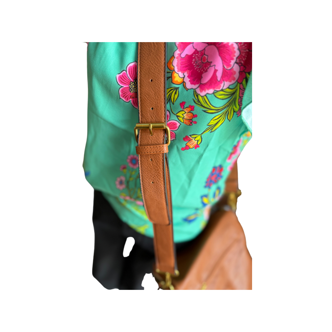The Megan Sling Bag in brown vegan leather with adjustable strap. Available in S, M, and L sizes.