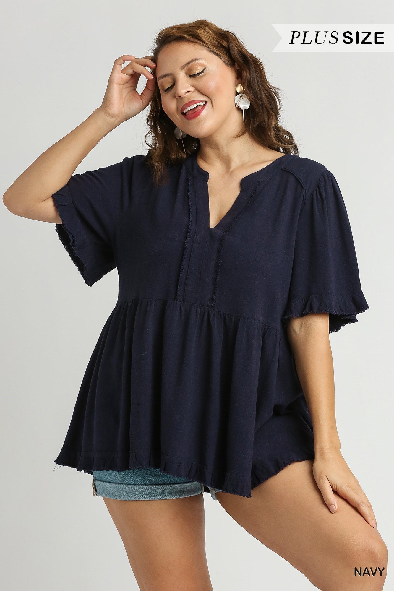 This is a Linen V-Neck Pleated Top with Ruffle Sleeves & Fray Details. The top features ruffled sleeves and delicate fray details, making it a unique addition to any wardrobe. It is available in plus sizes.