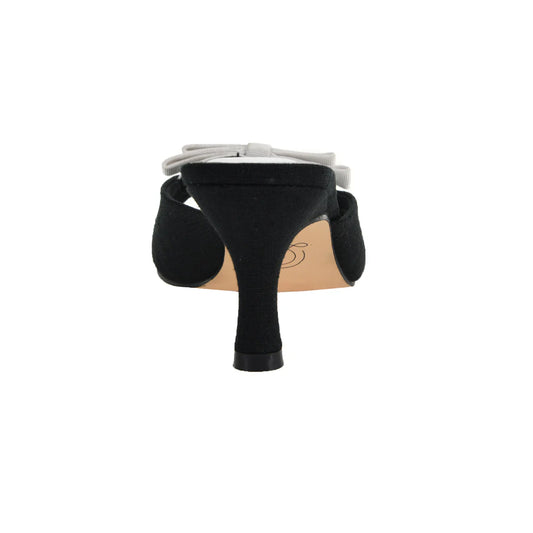 The Yolana Heel - Black/White Mule features a black design with a light-colored bow on the rear. It has a slender heel and smooth finish. Available sizes: 5-11.