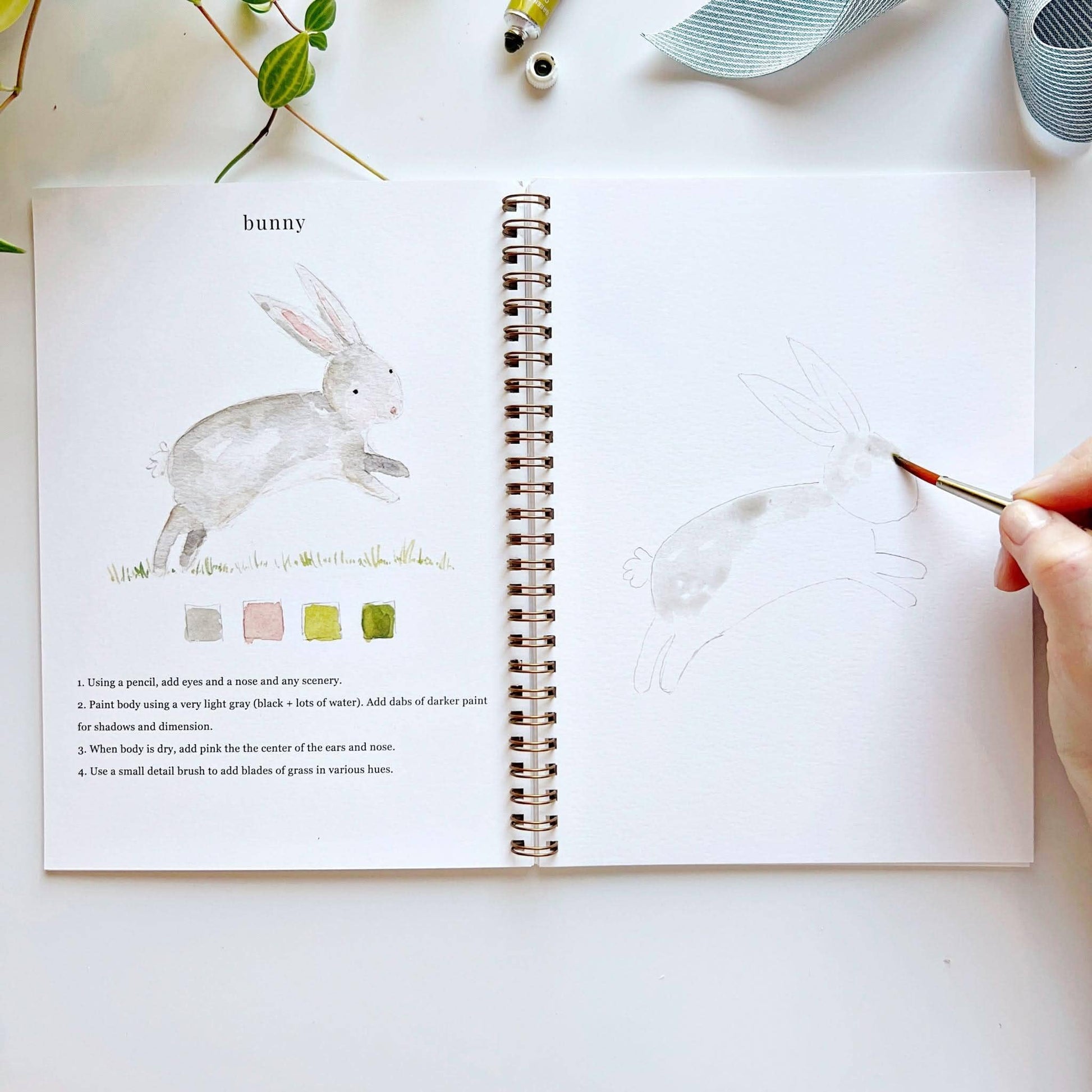 Animals Watercolor Workbook open to bunny instructions and sample; available in standard A4 and A5 sizes.