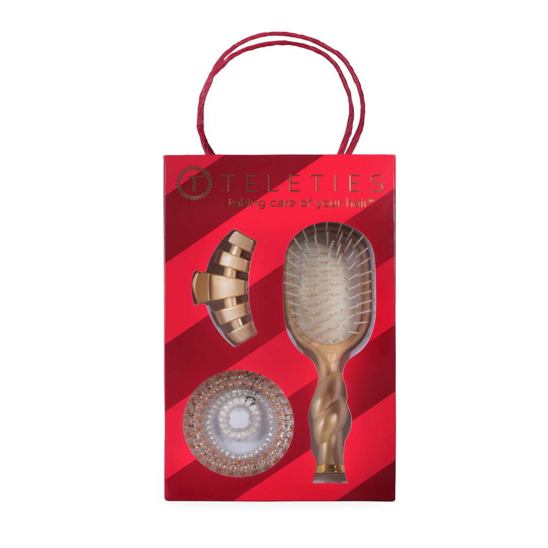 Holiday Brush Gift Set with mini brush, gold hair clip, and coiled hair ties in red striped bag.