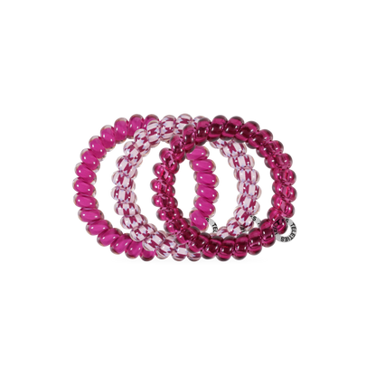 Three Merlot after Midnight Large Hair Ties in spiral coil designs—two pink, one clear with pink accents. All are no-crease; one features a small silver tag. Available in large size.