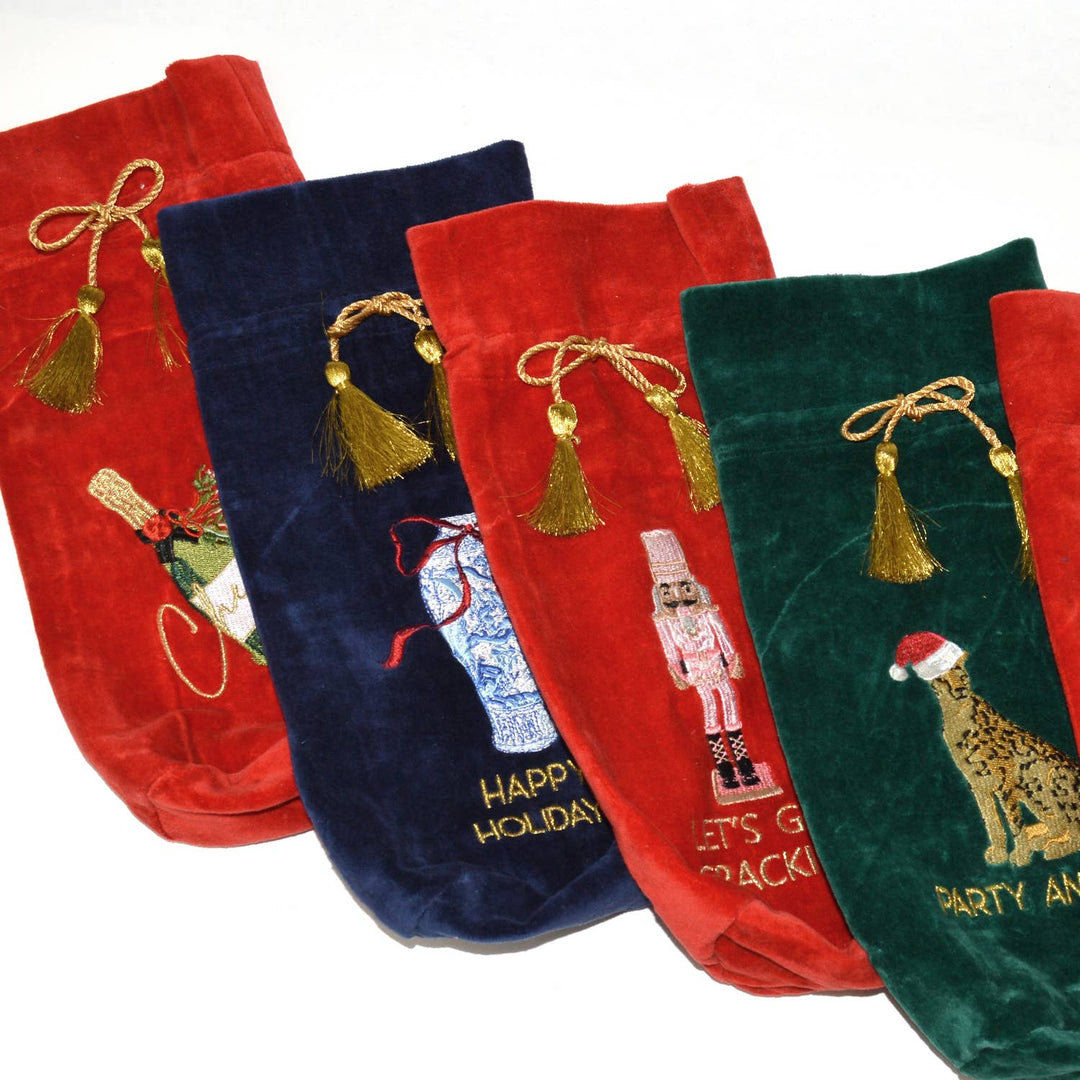 Five velvet wine bags, including the Ginger Jar Blue Embroidered Wine Bag, in red, blue, and green, each with a gold drawstring tassel and festive embroidery.