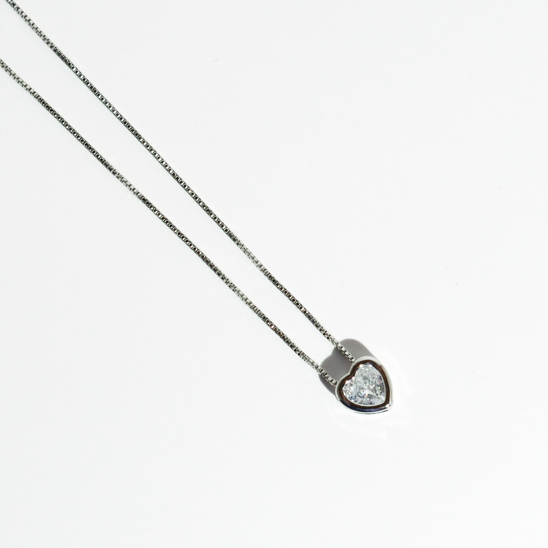 The Tiny Love Necklace: Silver has a heart-cut crystal pendant on a silver chain with sparkling gemstone. Available in 16", 18".