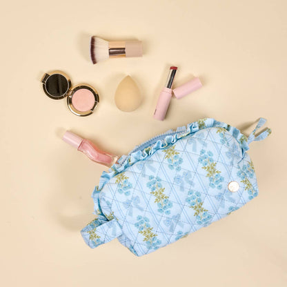 The Essentials Quilted Cosmetic Pouch–Oh So Fancy Blue has a blue floral quilt, ruffled edge, wipeable interior. Sizes: S/M/L.