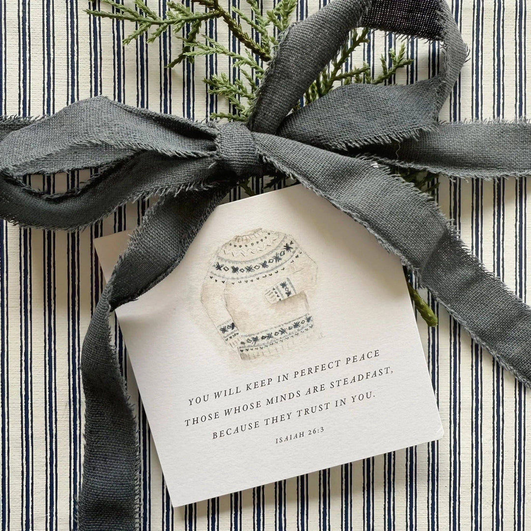 Striped gift with dark gray ribbon, greenery, and a cozy sweater tag. Available in small and large sizes.