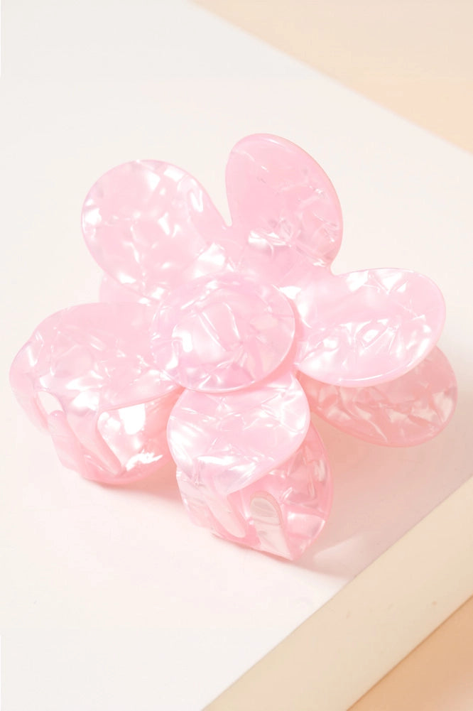 The Daisy Pearlized Hair Clip is a pink flower-shaped hair accessory with a marbled, glossy texture and slightly translucent, pearlescent petals. Sizes available: One Size.