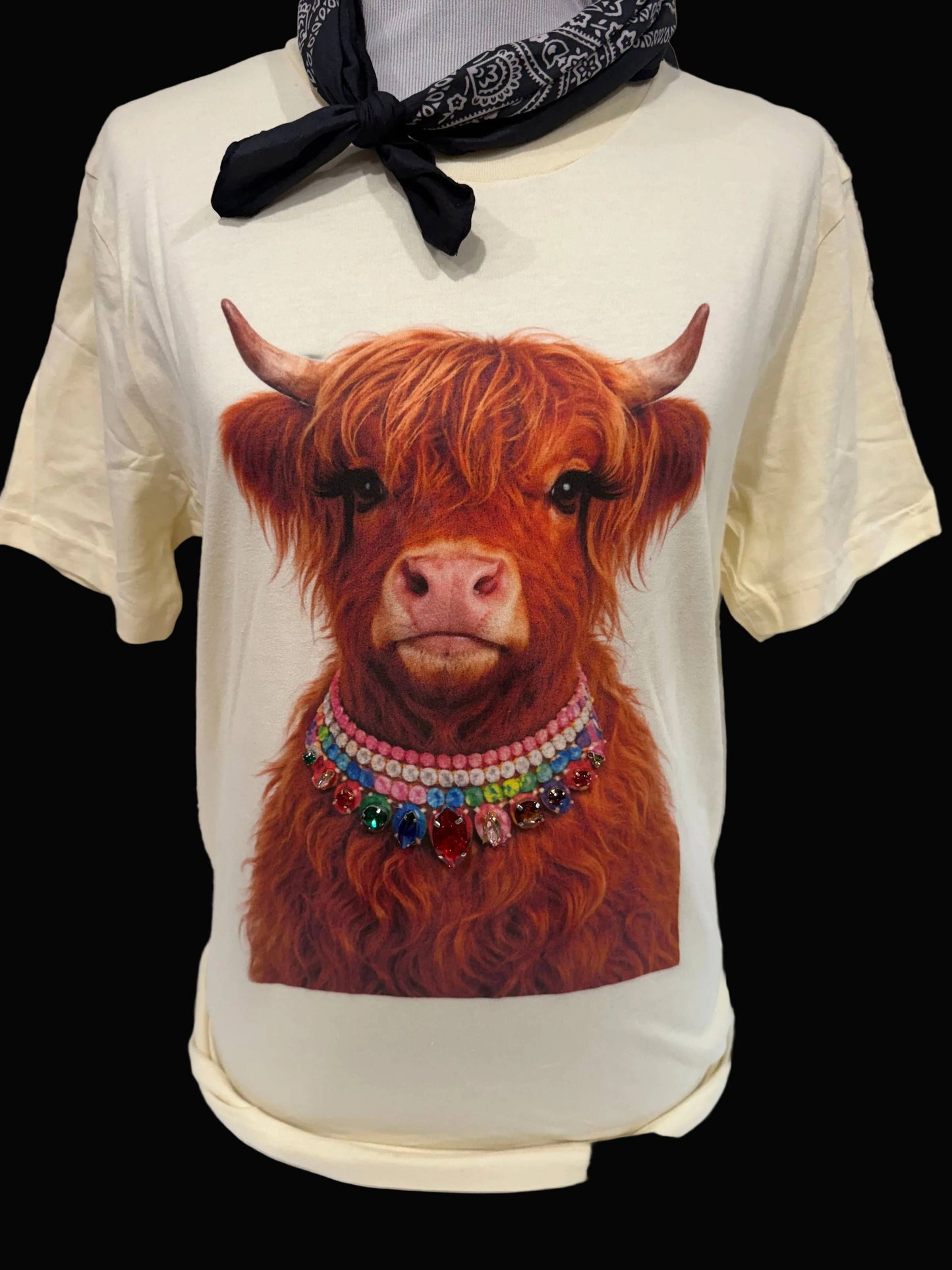 Light pink crewneck T-shirt, size 2XL, called "Jeweled Collar Highland Calf," features a graphic of a Highland calf with a colorful jeweled collar. No additional bling. Available in sizes 2XL and colors white, natural, or light pink.