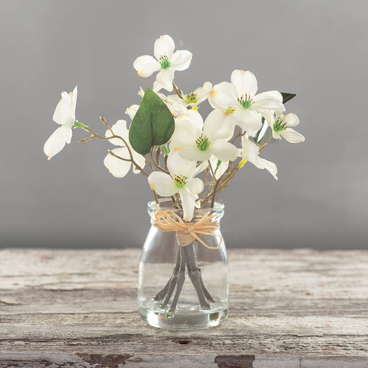 Small glass vase with white dogwood blooms and green leaves, tied with twine. Available in small, medium, and large sizes.