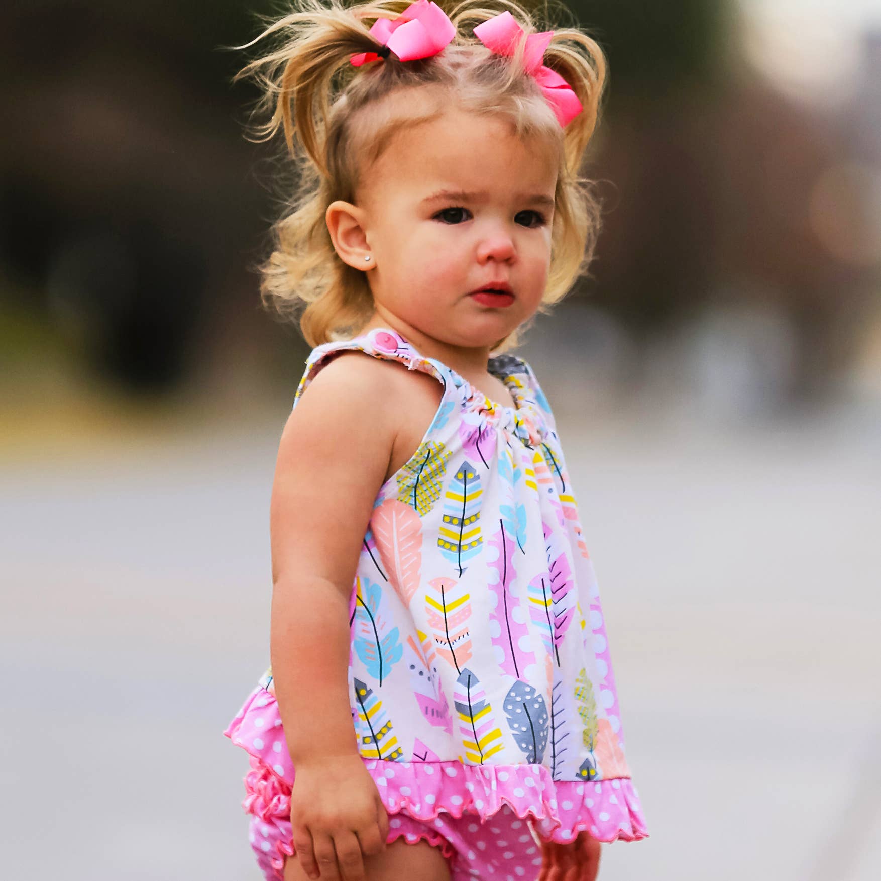 Young baby modeling top with matching bloomers (sold seperately). Baby has pink bows in her hair.