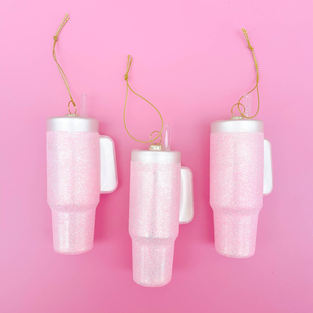 Three pink glittered tumbler Christmas ornaments with straws and gold strings.