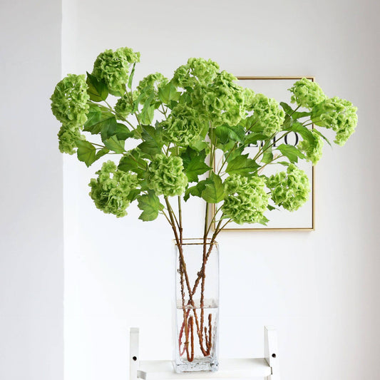 Clear glass vase with long stems of vibrant 40" Premium Faux Snowball hydrangea spray in green. Sizes available: 40".