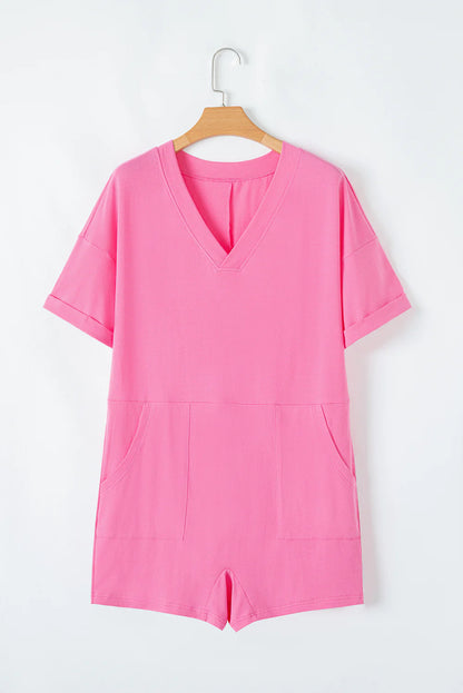 Pink loose half sleeve V neck knit romper with cuffed sleeves, two front pockets, and stretchy fabric. Available in sizes S, M, L.