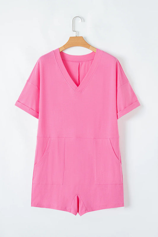 Pink loose half sleeve V neck knit romper with cuffed sleeves, two front pockets, and stretchy fabric. Available in sizes S, M, L.