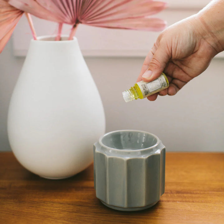 Sweet Grace Home Fragrance Oil is poured into a gray ceramic diffuser; available in multiple sizes. Flameless fragrance solution shown.