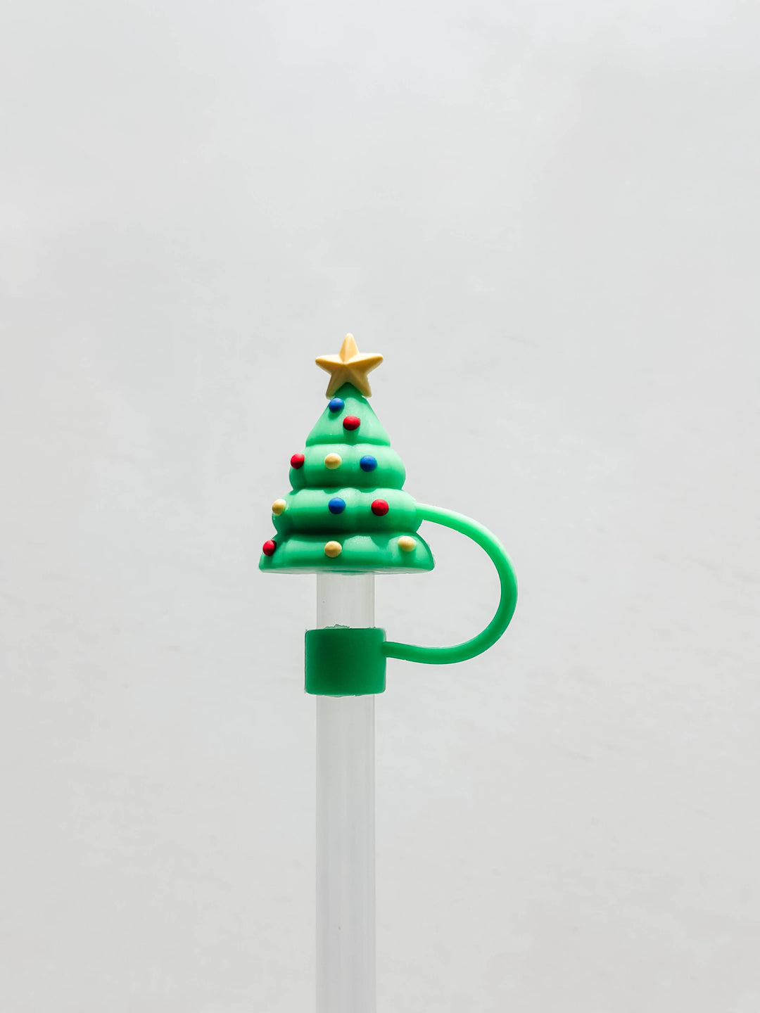 Green silicone Christmas tree straw cover with a yellow star and colorful ornaments.