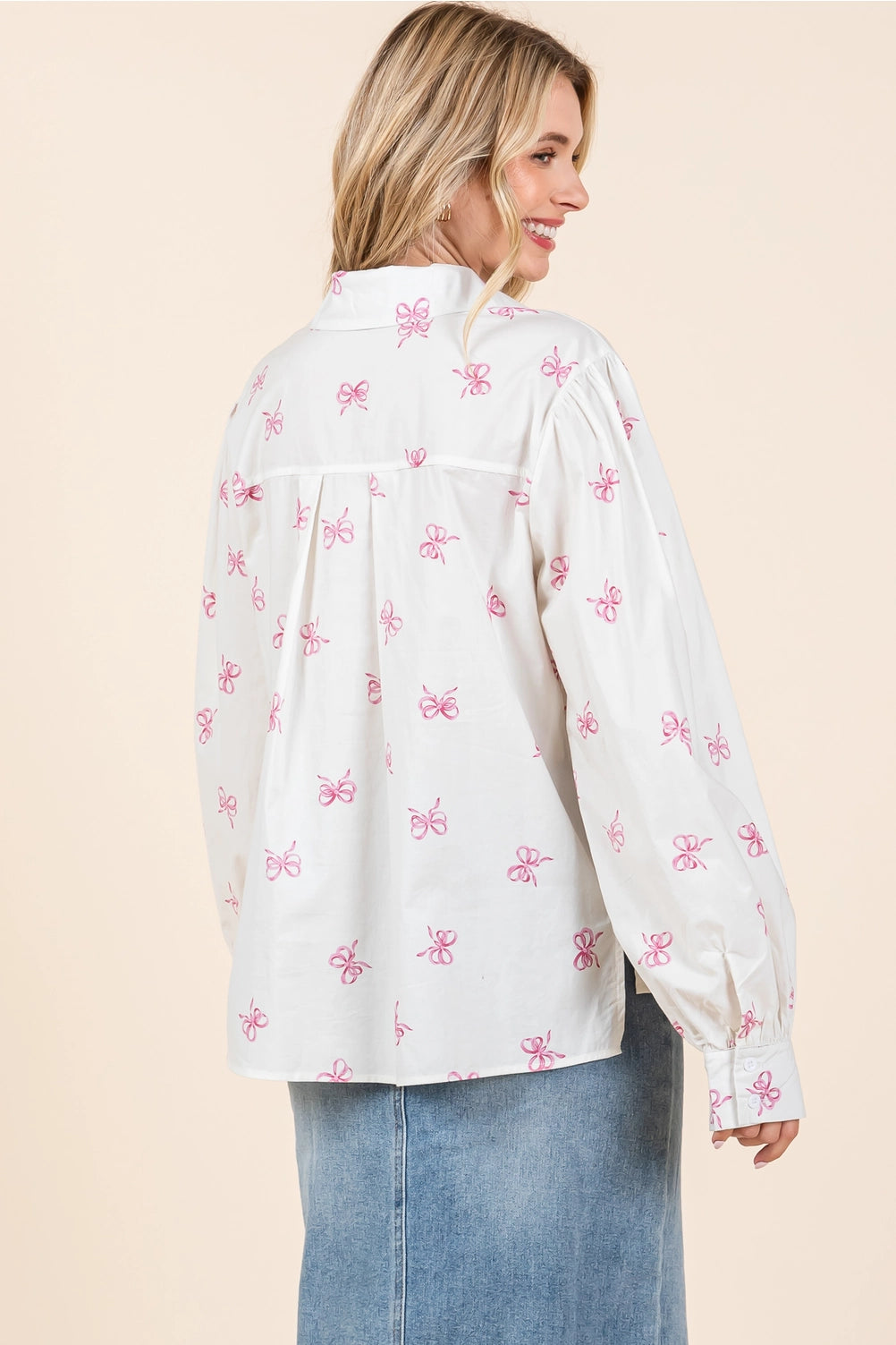 The Ribbon Bow Print Button-Up Blouse is a stylish top featuring a delicate bow print and button-up design. Available sizes: XS, S, M, L, XL.