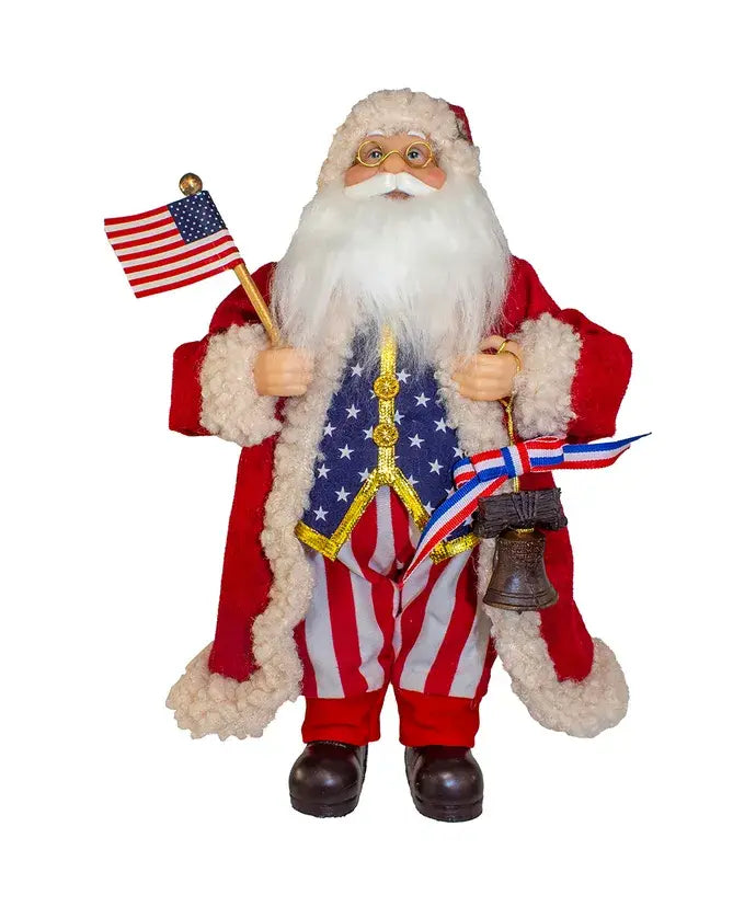 12" 1776 American Santa Tablepiece collectible, dressed in a red, white, and blue outfit with stars and stripes, holding an American flag and a bell with ribbon.