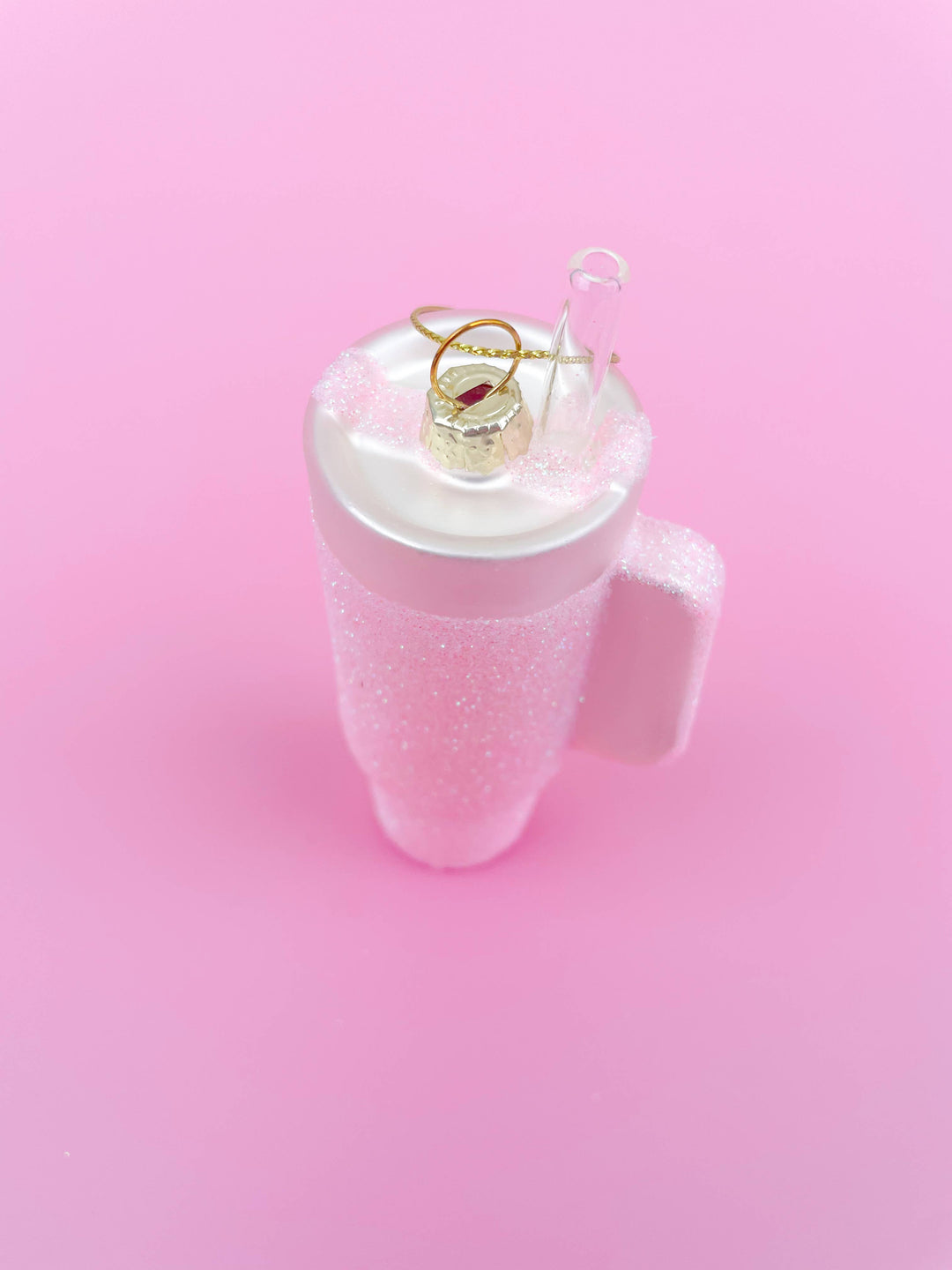 Pink glittered tumbler Christmas ornament with clear straw and gold hanging loop.