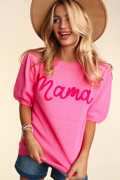 A joyful woman in a Mama Embroidered Pop Letter Short Bubble Sleeve Sweater with denim shorts and a hat, smiling broadly in a studio setting.