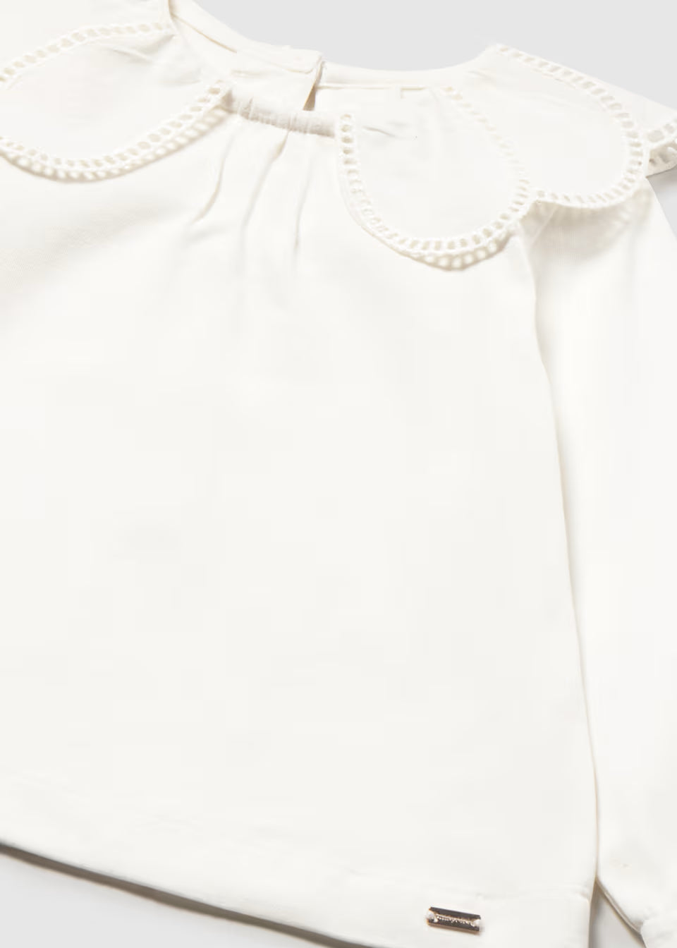 White blouse with scalloped Peter Pan collar, eyelet trim, smooth fabric, balloon sleeves, and subtle metallic brand tag near hem. Available in sizes 2T-6.