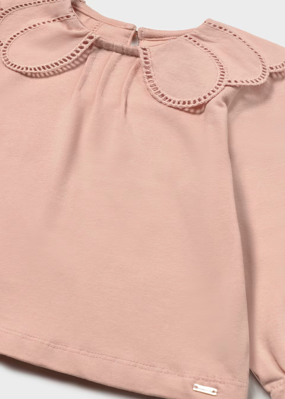 Light pink long-sleeve shirt with scalloped embroidered petal collar, eyelet trim, and small metallic tag at bottom hem. Available in sizes 2T-6.