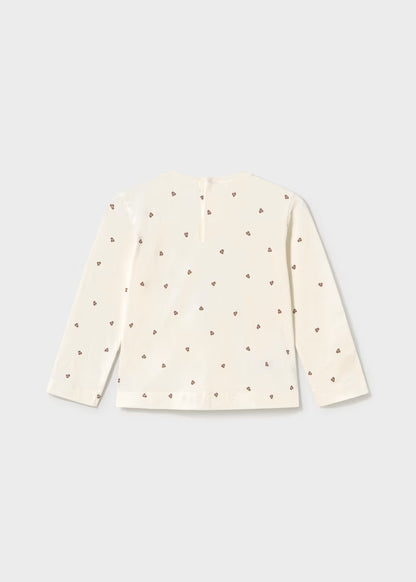 Cream long sleeve T-shirt with straight hem, decorated on the back with small brown heart patterns and glitter dots. Available in sizes 2T-6T.