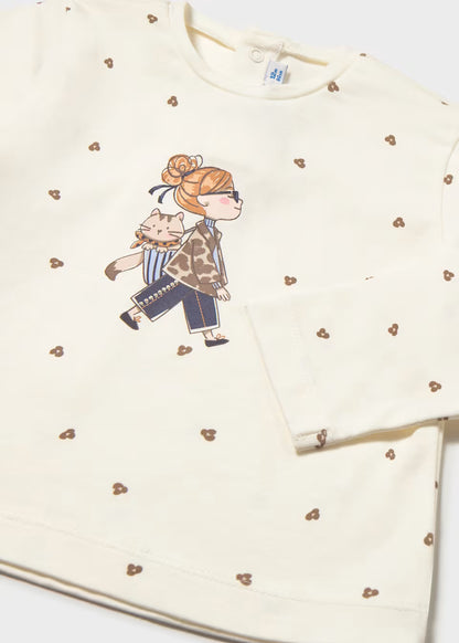 Cream-colored long sleeve T-shirt with small brown heart motifs, central print, and glitter dot accents. Available in sizes 2T-6T.
