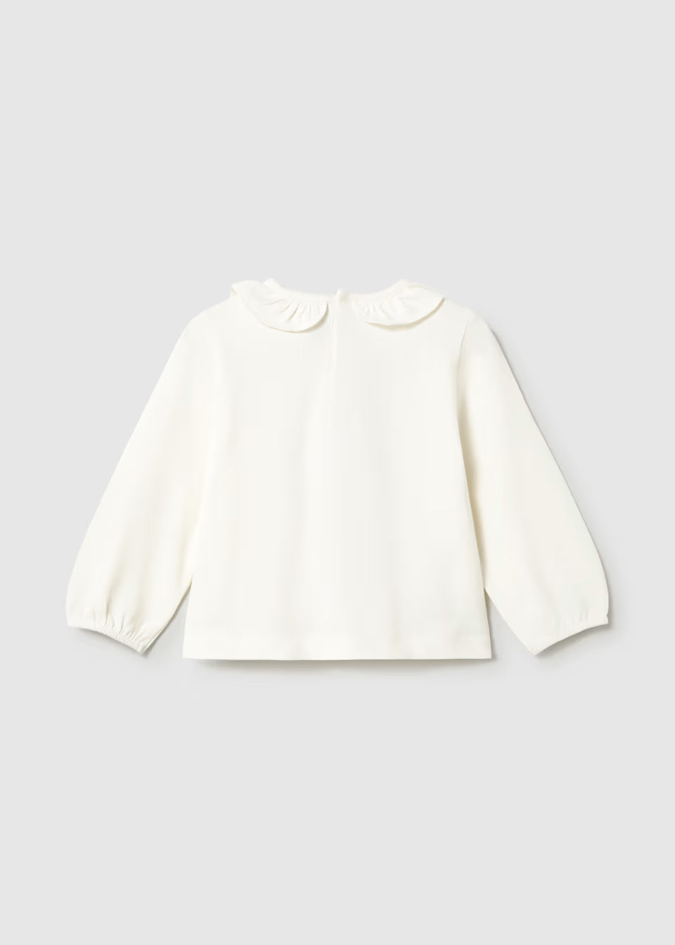 White, loose fit long sleeve T-shirt with elasticized cuffs and a ruffled Peter Pan collar. Available in sizes 80-120.