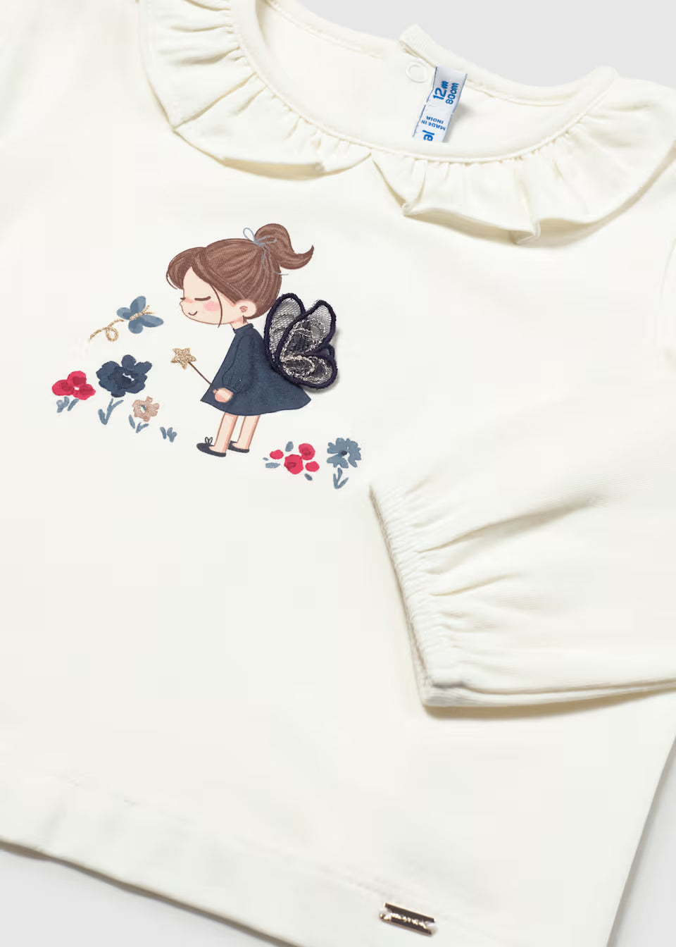 White long-sleeve baby shirt with ruffled Peter Pan collar, fairy print, and 3D sewn-on wings. Available in sizes 0-24 months.