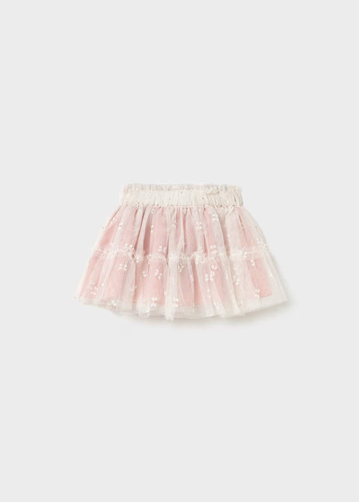 Pink tulle skirt with white floral embroidery, embroidered butterflies, layered design, and elastic waistband. Available in sizes 2T-5T.