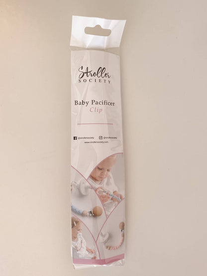 Packaging of a Pacifier Clip - Pink and Blue baby pacifier clip, featuring photos of infants using the product and social media contact information on a soft beige background. Each clip is made from BPA-free