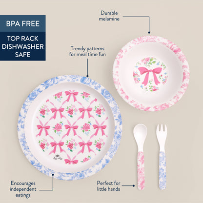 Itzy Bistro™ 4-piece set: blue/pink floral plate, pink bowl with bow, matching spoon and fork. BPA-free. Dishwasher safe. Sizes vary.