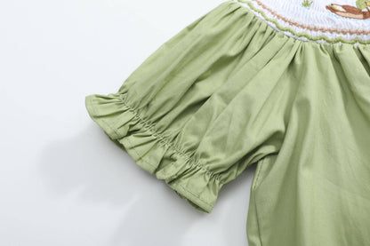 Close-up of puff sleeve with ruffled elastic trim and intricate smocked detailing near the shoulder on the Pistachio Green Mallard Duck Smocked Bishop Dress, available in size 18-24M.