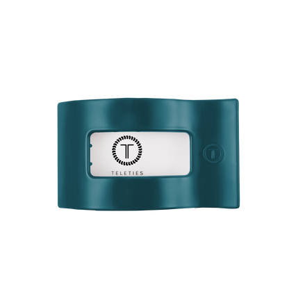 Teal flat rectangular hair clip with a center window displaying the TELETIES logo in black on white; available in medium size.