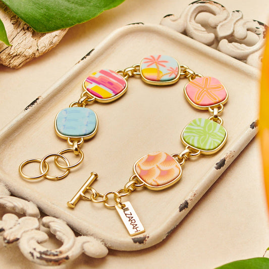 Palm Beach Reversible Coin Bracelet: Rectangular charms with colorful, abstract floral designs; reversible coin-shaped bezels in Seaside Green under matte gold plating; small gold tag engraved "LIZARDY." Sizes available: One size fits most.