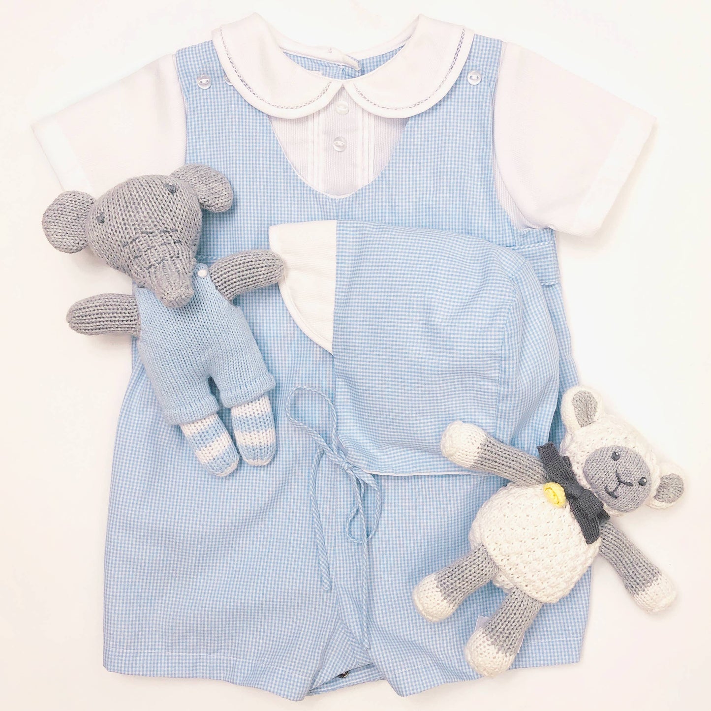 Blue romper shown with matching hat (included) and styled with blue elephant and white lamb (not included).