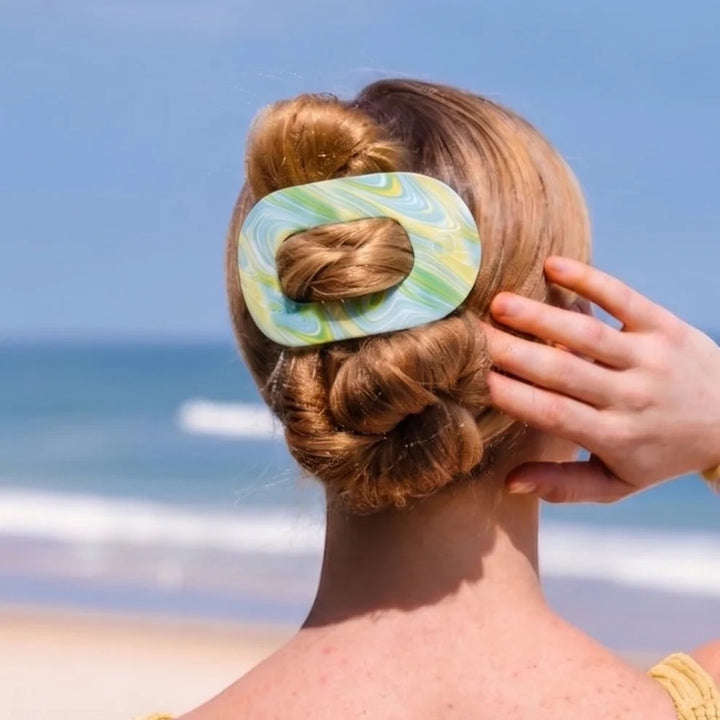 Summer Tie Dye Edition Flat Round Hair Clip securing a bun; available in small, medium, and large sizes.