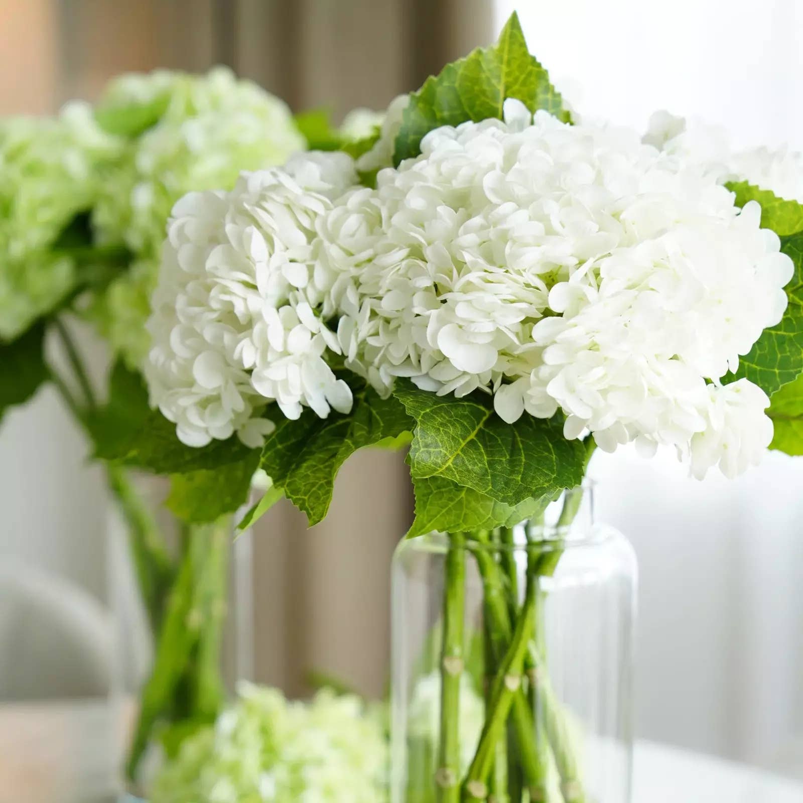 12.5" lifelike Real Touch Hydrangea with 6” soft pink bloom and lush leaves in a clear glass vase.