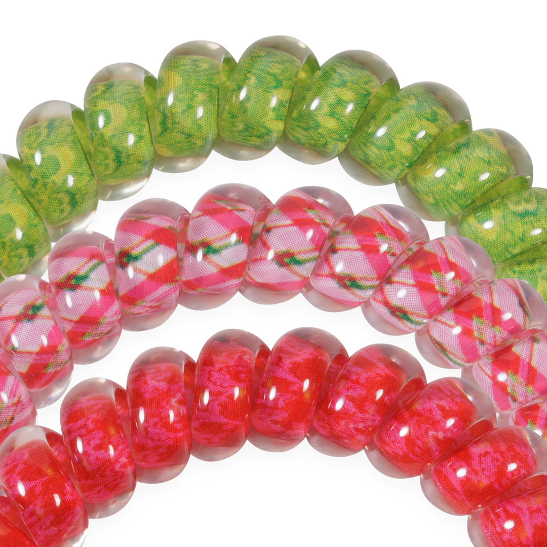 Three large spiral coil hair ties in green, pink plaid, and red.