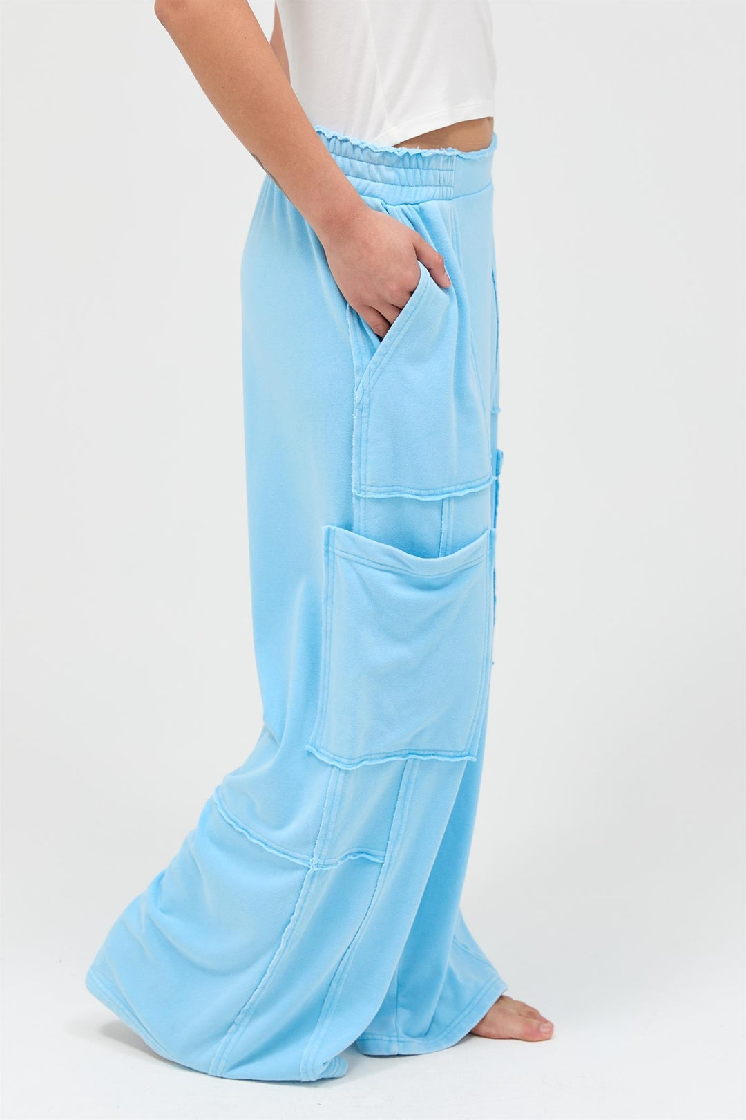 Light blue mineral wash wide leg cargo pants with large front pockets, visible seams, high-rise; sizes XS-XL.