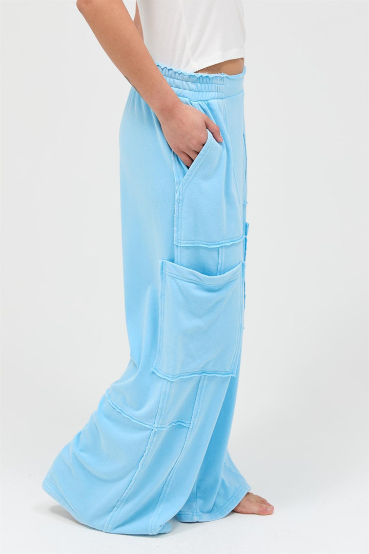 Light blue mineral wash wide leg cargo pants with large front pockets, visible seams, high-rise; sizes XS-XL.