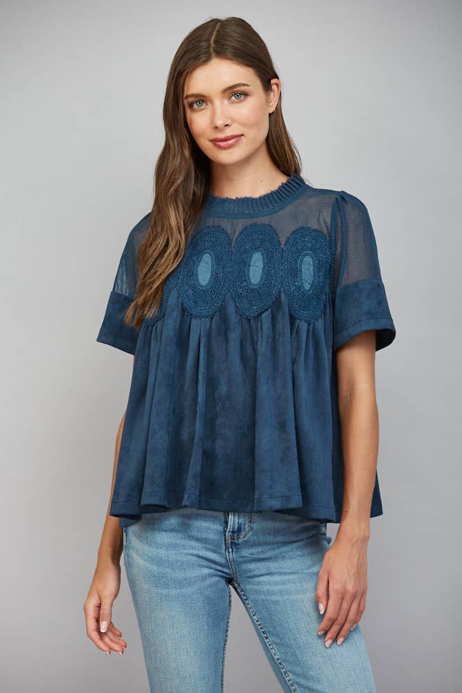 Teal blue short-sleeved faux suede top with a sheer mesh yoke, ruffled collar, and three circular lace appliques across the chest.