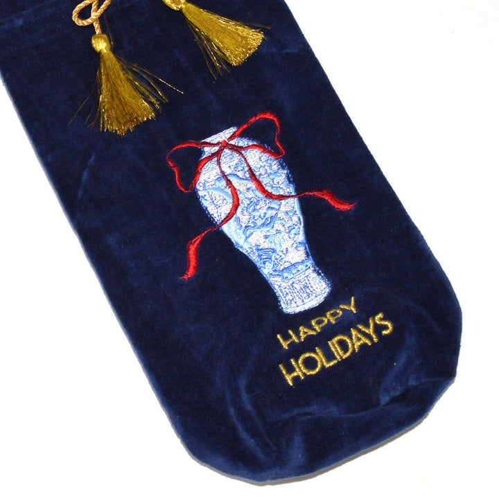 Dark blue velvet wine bag featuring an embroidered blue and white ginger jar with a red bow, “HAPPY HOLIDAYS” in gold text, and gold tassels.