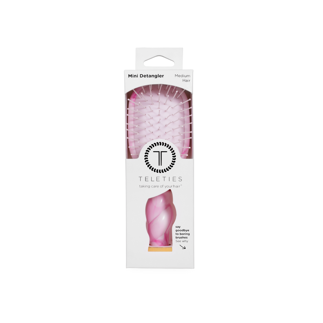 Pink Mini Detangler Brush in medium size, visible through a clear window in white TELETIES packaging with branding and brief product details.