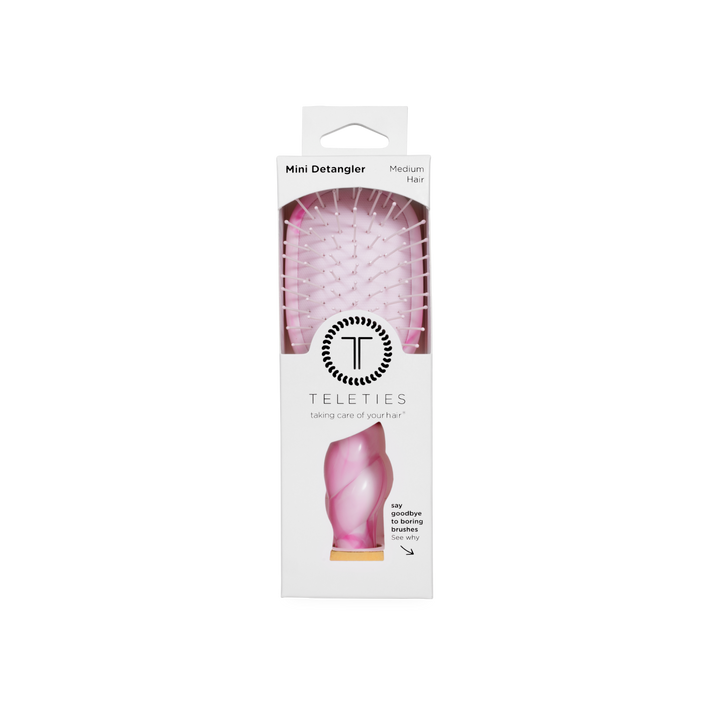 Pink Mini Detangler Brush in medium size, visible through a clear window in white TELETIES packaging with branding and brief product details.