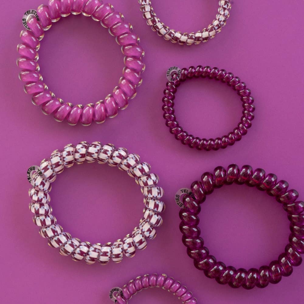 Six Merlot after Midnight Large Hair Ties in pink and purple, available in one large size. Includes solid and striped designs with a gentle, no-crease hold.
