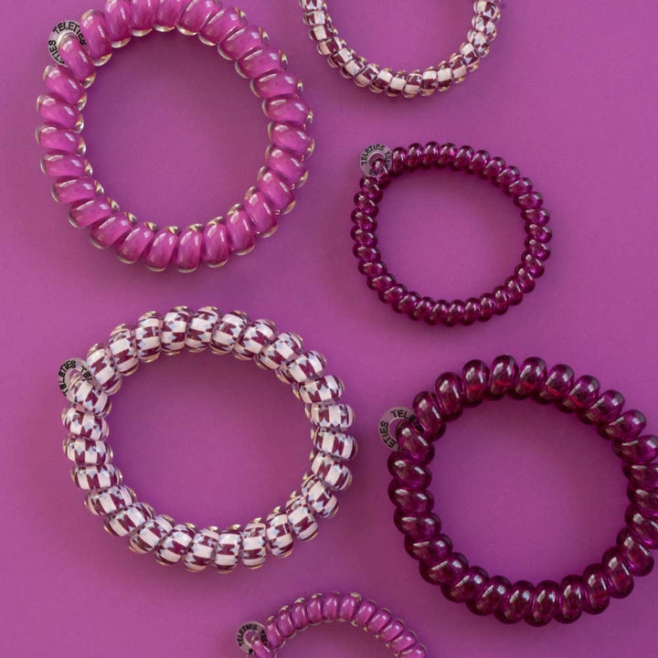 Six Merlot after Midnight Small Hair Ties in pink, purple, and two-tone designs; no-crease styling. Available in small size.