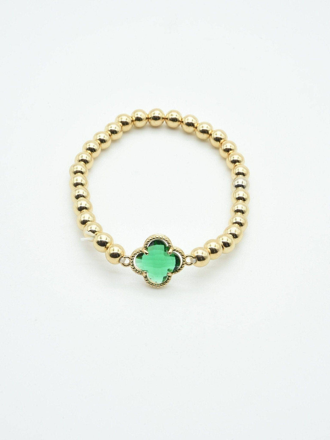 Gold beaded bracelet with a green crystal clover charm. Available in sizes S, M, and L.